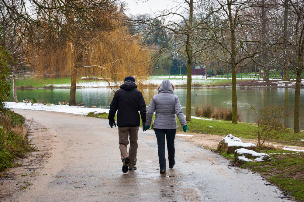 Two people walking together on a park path in winter.
