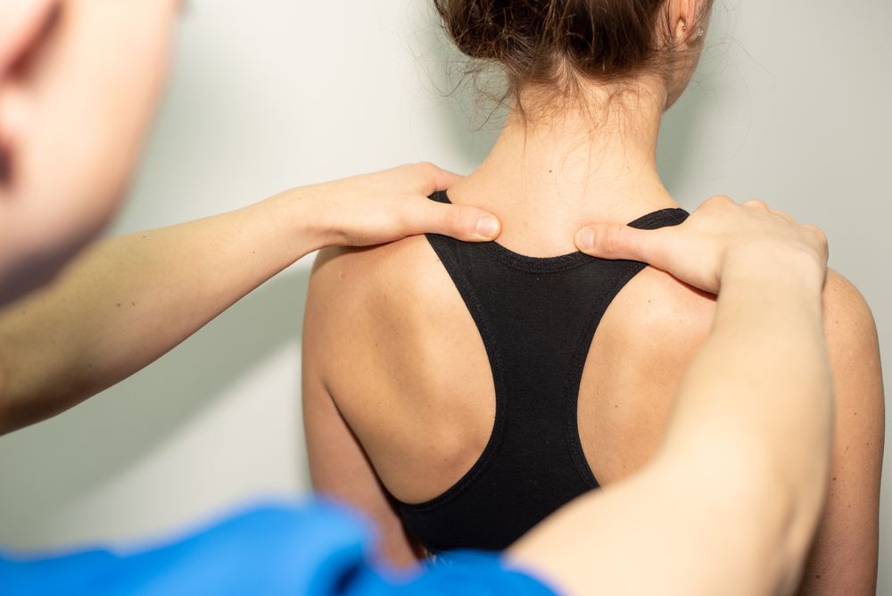 Kinesiology tape applied to the upper back and shoulder.