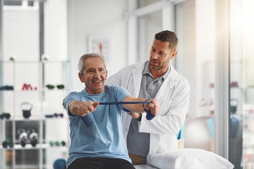 Therapist coaching a resistance band exercise in a clinic.